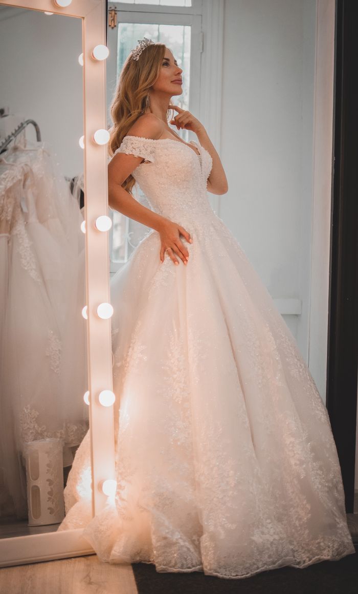 services-01 Bride in wedding gown posing elegantly by mirror, showcasing exquisite lace details.
