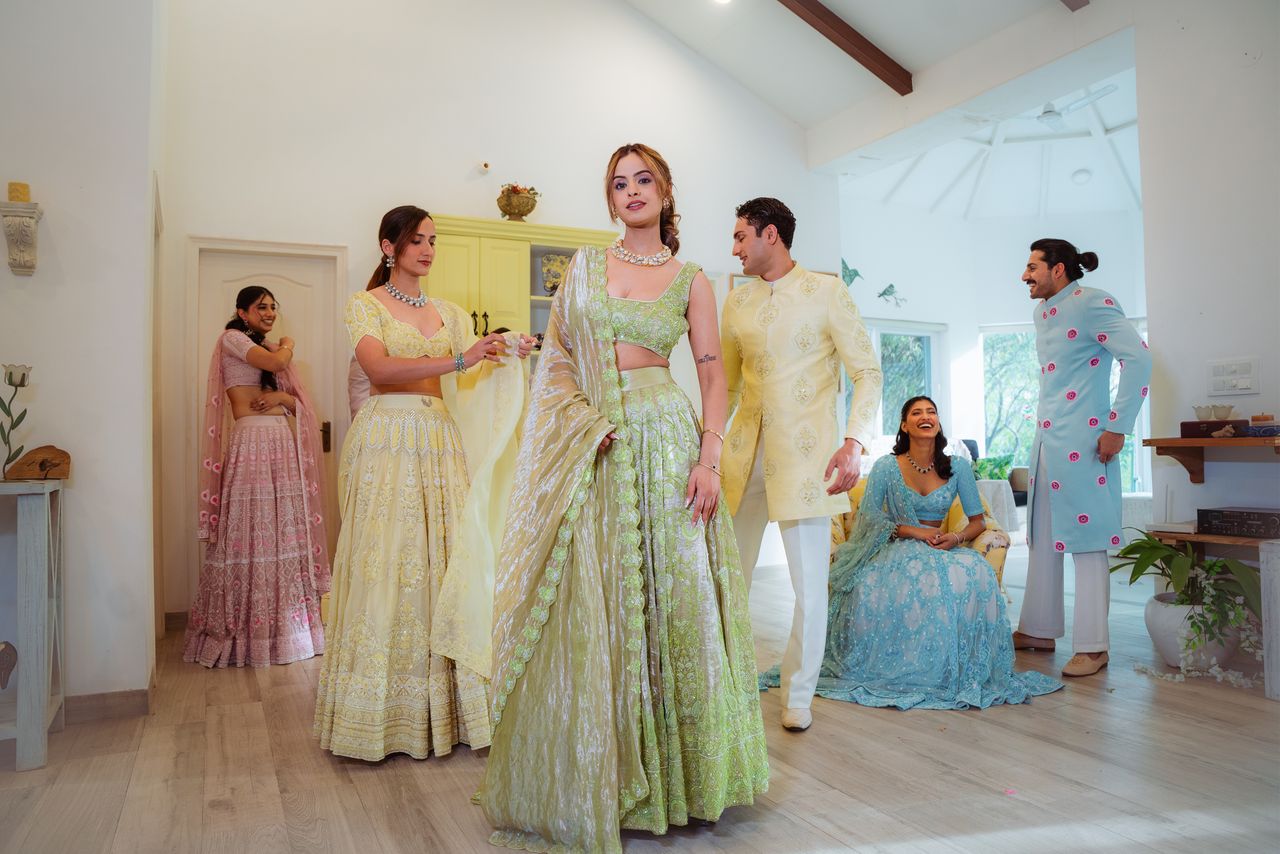 who-we-are A group of adults in vibrant traditional Indian attire gathered indoors in a well-lit room.