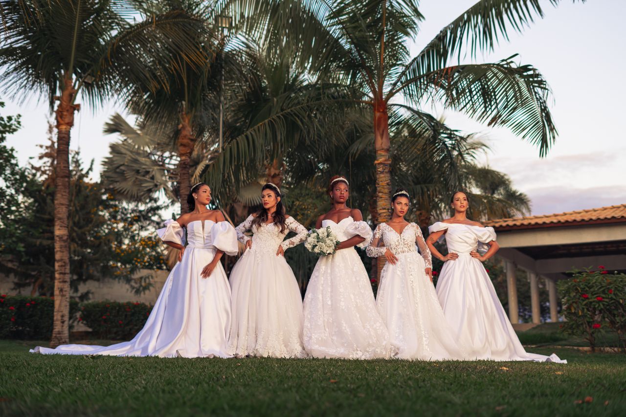services-02 A group of bridesmaids in elegant white gowns posing outdoors amidst palm trees.