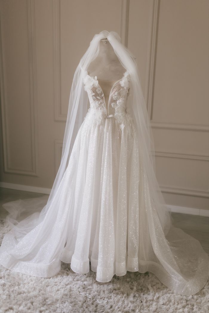 journey Sophisticated white wedding gown displayed on mannequin in soft light.