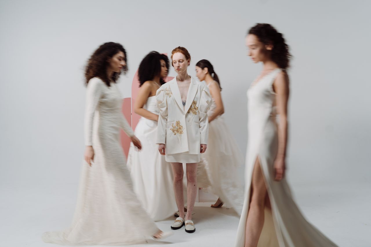 services-03 Stylish women in elegant dresses and jackets captured in motion during a studio fashion shoot.